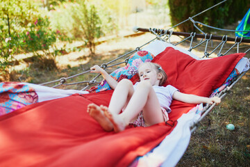 Adorable preschooler girl resting in hammock outdoors