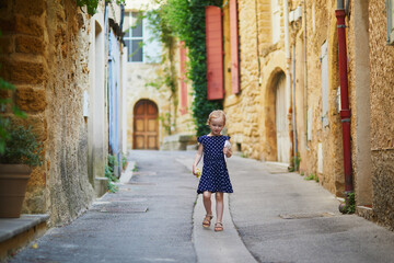 Fototapeta na wymiar Adorable preschooler girl walking on a street of Medieval village of Lourmarin in Southern France