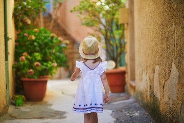 Obraz premium preschooler girl in white dress and straw hat on a street of Bonnieux village in Provence, France