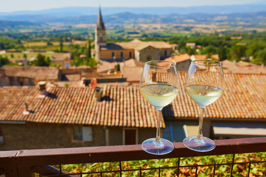 Two Glasses Of White Wine With View To Beautiful Old Roofs Of Bonnieux Village In France