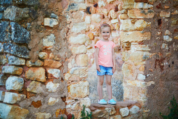 preschooler girl having fun near brick wall in Roussillon, Provence, Southern France