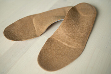 orthopedic insoles for shoes brown, made of natural materials, lies on a light surface of the table. Prevention and treatment of flat feet, shoe accessories