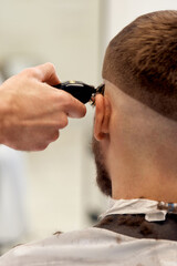 Barber trim hair with clipper on handsome bearded man