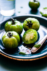 Green tomatoes with fresh salt on blue plate.
