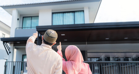 Fototapeta na wymiar Loving young couple looking at dream house. Portrait of an excited Muslim couple standing outside their new home, walking on the model new house