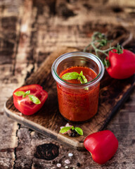 Tomato sauce with fresh tomatoes with pepper and basil on wooden background.