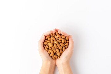 Overhead shot of woman’s hands holding almonds isolated on white background