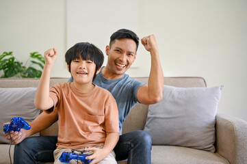 Joyful Asian dad and son with joysticks are playing video games