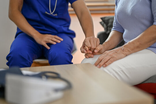 Cropped image of a kind doctor holding or touching a patient's hand to comfort and support.
