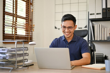 Fototapeta premium Happy Asian businessman working on his business project on laptop at his desk in the office.