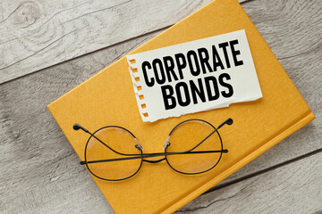 CORPORATE BONDS torn paper on a yellow notebook. near glasses.