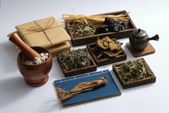 Some wooden trays with many types of herb placed on, displayed with earthen pot, medicine packs, ancient Chinese medicine books, mortar and pestle. Chinese herbal therapy to enhance health condition