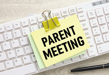 Parent Meeting yellow sticker with a clip on a white keyboard. text in black