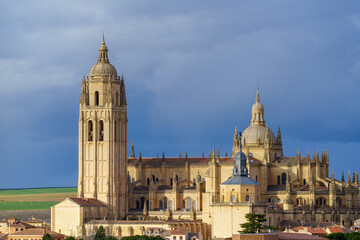 Naklejka premium Tower of the cathedral church of Segovia with blue sky and clouds in the background and birds in flight