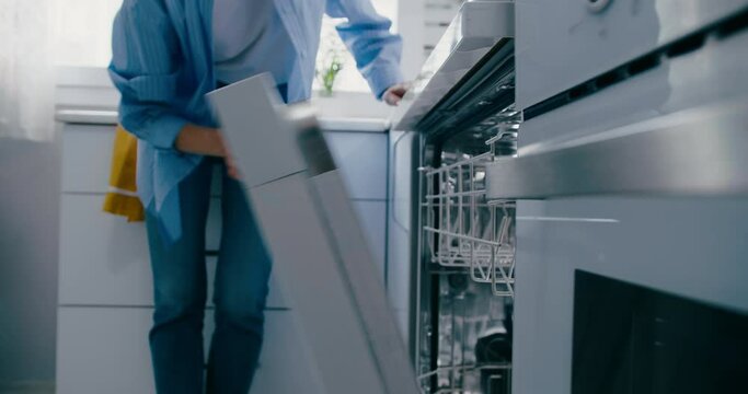 White woman loading dishwasher of dirty dishes, close-up shot