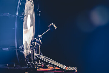 Bass drum with pedal, musical instrument on black background.
