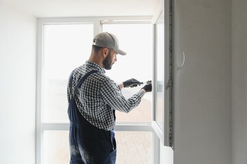 Naklejka na ściany i meble Construction worker installing window in house