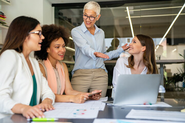 Smiling diverse colleagues gather in boardroom brainstorm discuss financial statistics together