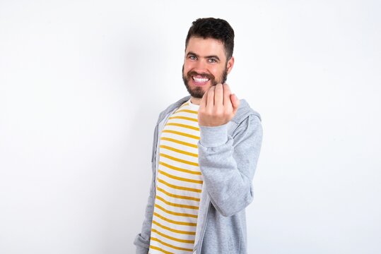 Young caucasian mán wearing trendy clothes over white background inviting to come with hand. Happy that you came