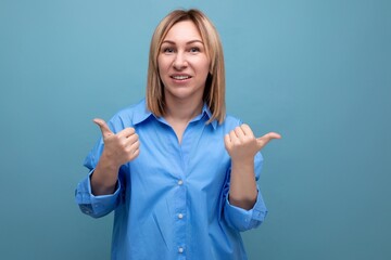 informal blond young millennial in casual shirt shows hands super on blue background with copy space