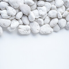 White pebble stones on white background with copy space.