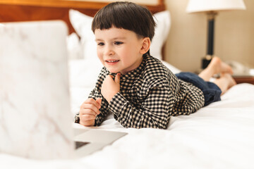 Little boy with laptop training pronounce letters at home. Family enjoy distant talk by video call, spend time on internet, online education concept. Boy looking at the laptop, video call with someone