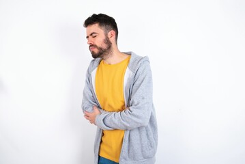Young caucasian mán wearing trendy clothes over white background got stomachache