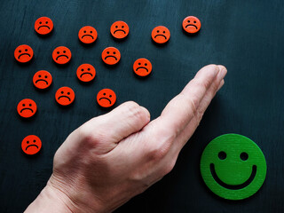 The hand protects the joyful emoticon from the sad ones. Emotional regulation concept.