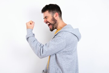 Portrait of funny Young caucasian mán wearing trendy clothes over white background shout yeah...