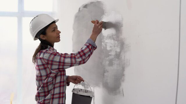 Woman painting wall with paint brush. Painting apartment, renovating with color paint