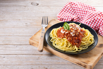 Spaghetti with bolognese sauce on wooden table. Copy space