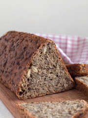 Loaf of tiangular wholegrain bread on a wooden board close up. Copy space.