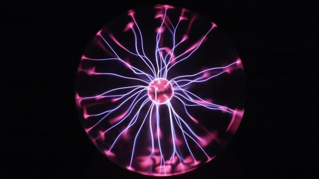 Plasma globe in slow motion. Blue and purple light beams and energy rays inside the ball. Full sphere on black background. Tesla coil electric discharge.
