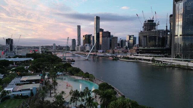 Drone shot of Brisbane's South Bank Beach and Parklands. Camera rotating around the artificial beach. Brisbane City River in background. Queens Wharf Casino and Neville Bonner Bridge in construction.