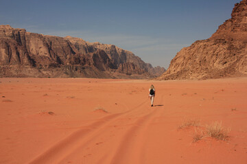 Obraz na płótnie Canvas One woman walking in a Wadi Rum desert in Jordan, taken from the back