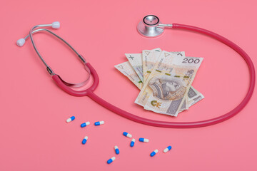 Drogie koszty leczenia - gotówka z lekarstwami i stetoskopem na różowym tle