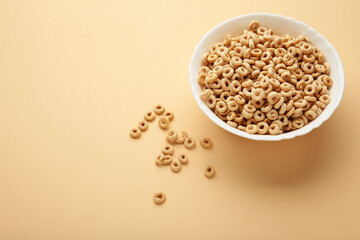 Bowl of sugar-coated corn flakes on beige background.