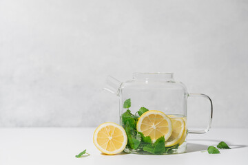 Melissa tea with lemon in glass teapot on white background. Natural, healthy tea concept
