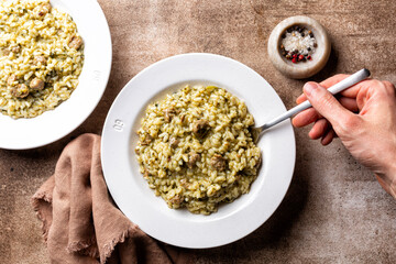 Eating italian rice dish risotto with sausage and turnip greens, risotto con Salsiccia.  Mans hand holding a fork.