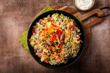Couscous with vegetables and beef tongue meat, homemade salad with marinated bell pepper, zucchini, celery, onion, carrot. Mayonnaise sauce. Dark brown table.