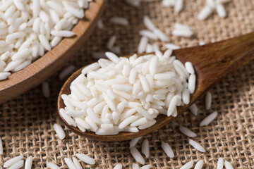 Organic raw sticky rice or glutinous rice in wooden spoon on table