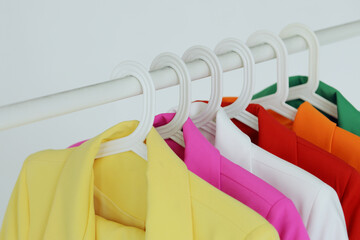 Multi-colored bright jackets on a hanger on a white background.