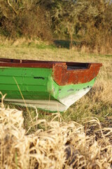 Fototapeta na wymiar Close up of back of small green wooden row boat aground in field near Lough Colgagh, County Sligo, Ireland on springtime evening