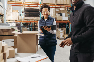 Happy warehouse employees fulfilling orders using a warehouse management system