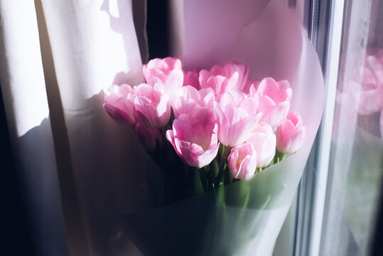 A bouquet of flowers in a vase. Pink tulips. Spring. A vase with flowers on the windowsill.