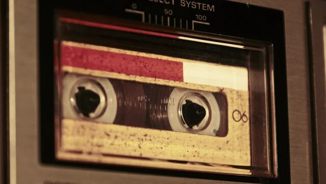 Audio cassette playback in vintage tape recorder. Record player playing old yellow audio cassette, close-up. Retro tape reels rotate in deck. Recording conversations, 80s, archive playback, call