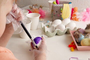 Children's hands paint Easter eggs with elements of spring decor table top view