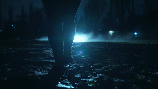 A people walks along the alley of the night city after the rain through the fog