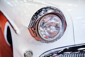 Roung headlight of white retro car.