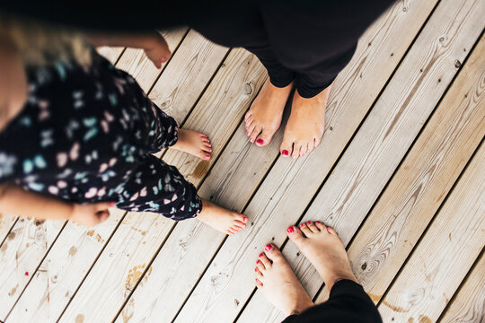 Low section of barefoot women and girl (2-3) standing